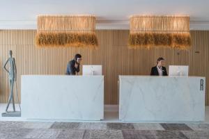 two people standing behind reception desks in a room at Aroeira Lisbon Hotel - Sea & Golf in Aroeira