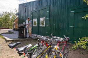 un uomo in piedi fuori da un edificio verde con le biciclette di Sundog Retreat a Whitehorse