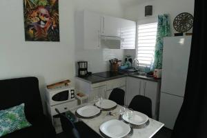 a small kitchen with a table with plates on it at AnseMitan beach studio,Clim,wifi, 200mplage 3îlets in Les Trois-Îlets