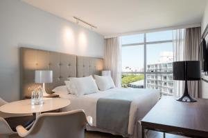 Habitación de hotel con cama, mesa y ventana en Vivaldi Hotel Loft Punta Carretas, en Montevideo