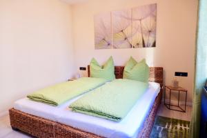 a wicker bed with green pillows in a room at City Flair in Dresden