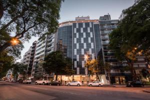 un edificio alto con coches estacionados frente a él en Vivaldi Hotel Loft Punta Carretas en Montevideo