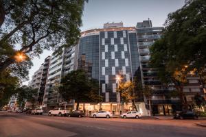 Un grand bâtiment avec des voitures garées devant lui dans l'établissement Vivaldi Hotel Loft Punta Carretas, à Montevideo