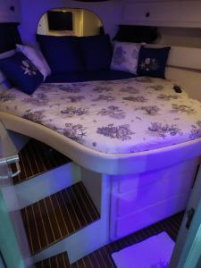- un lit au milieu d'une pièce avec éclairage violet dans l'établissement Sanremo charter boat and breakfast, à Sanremo