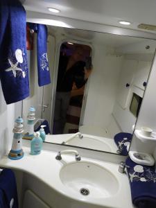 une femme prenant une photo d'un lavabo dans la salle de bains dans l'établissement Sanremo charter boat and breakfast, à Sanremo