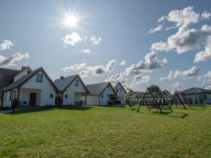 a yard with houses and a swing set in the grass at Domki u Bogdana in Dąbki