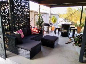 a patio with a couch and chairs and a grill at Cosy, self-contained and central to everywhere in Gold Coast