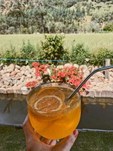 a person holding a glass with a drink at Caminhos da Serra do Tabuleiro - Chalé Araucária in São Bonifácio