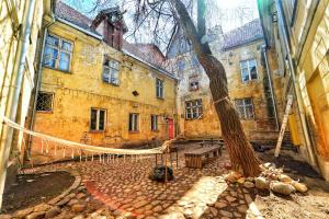 an old building with a tree in a courtyard at The Monks Bunk Hostel & Bar in Tallinn