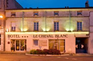 a hotel on the corner of a street at night at Cit'Hotel Le Cheval Blanc Cognac Centre in Cognac