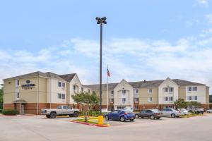 a hotel with cars parked in a parking lot at Candlewood Suites Beaumont, an IHG Hotel in Beaumont