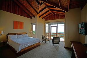 1 dormitorio con cama y ventana grande en El Establo Mountain Hotel, en Monteverde