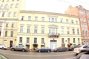 un gran edificio blanco con coches estacionados frente a él en Апартаменты "Антресоль", en San Petersburgo