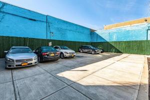 three cars parked in a parking lot next to a fence at Umbrella Hotel Brooklyn - Newly Renovated in Brooklyn