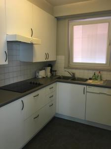 a kitchen with white cabinets and a sink and a window at LaurensaHeist in Knokke-Heist