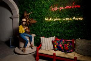 a statue of a woman sitting on a fountain in front of a green wall at Hotel Posada San Miguel in Jerez de García Salinas