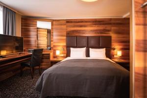 a bedroom with a bed and a desk and a television at Hotel Grauer Bär in Innsbruck +41 photos