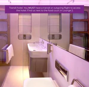 a bathroom with a sink, mirror, and toilet at YOTELAIR Amsterdam Schiphol Transit Hotel in Schiphol