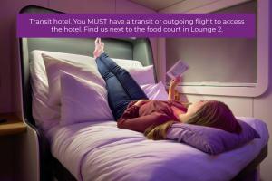 a woman laying on a bed on an airplane at YOTELAIR Amsterdam Schiphol Transit Hotel in Schiphol