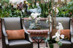 twee stoelen en een tafel met bloemen in de tuin bij Brent House Hotel in New Orleans