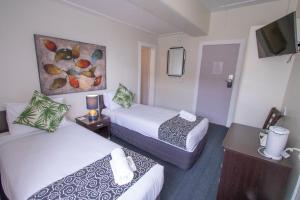 een hotelkamer met twee bedden en een tv bij Hotel Waterloo & Backpackers in Wellington