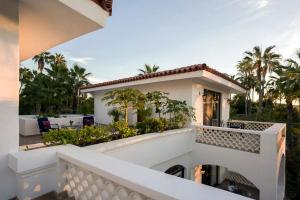 Dieses weiße Haus verfügt über einen Balkon mit Palmen. in der Unterkunft Hacienda Todos Los Santos in Todos Santos