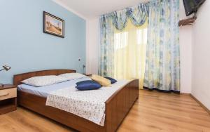 um quarto com uma cama com almofadas azuis e uma janela em Apartments Vola em Vrbnik