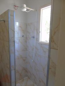 a bathroom with a glass shower with a window at Pousada Dona Maria in Areias