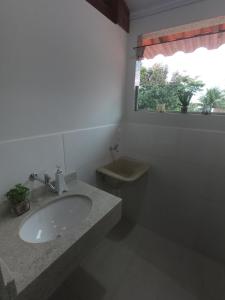 a bathroom with a sink and a toilet and a window at Recanto Guarassol Apartamentos in Sertão do Taquari