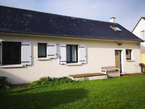a white house with a solar roof and a yard at Holiday Home Maison de l'Océan à Denneville in Denneville
