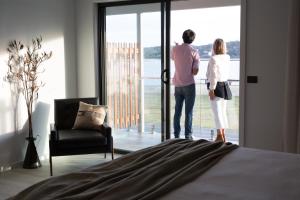 a man and a woman looking out of a bedroom door at The Seabird in Moruya