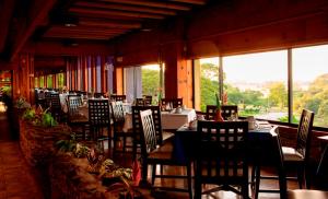 uma sala de jantar com mesas, cadeiras e janelas em Kapok Hotel em Port-of-Spain