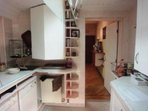 a kitchen with white cabinets and a hallway at Frank's Backpackers in Helmond