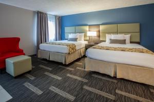 una habitación de hotel con 2 camas y una silla roja en Baymont by Wyndham Traverse City en Traverse City