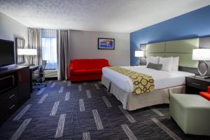 Baymont by Wyndham Traverse City في ترافيرس سيتي: غرفة فندقية بسرير كبير وكرسي احمر
