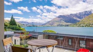 a table and chairs on a balcony with a view of a lake at Residence du Lac by Staysouth in Queenstown