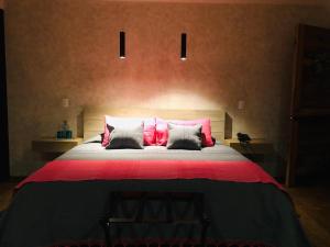 1 dormitorio con 1 cama grande con almohadas rosas y blancas en Múbú Hotel Boutique en Valle de Bravo