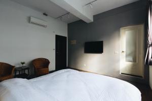 a bedroom with a bed and a television on the wall at 文創輕旅-近東大門夜市-車位免費可預約 in Hualien City