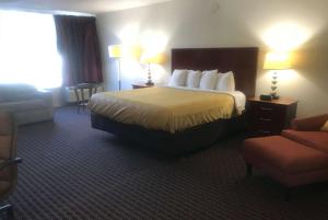 a hotel room with a bed and a chair at Days Inn by Wyndham Hartsfield Jackson Atlanta Airport West in Atlanta