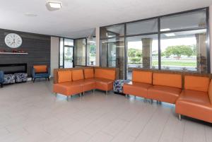une salle d'attente avec des chaises orange et une horloge dans l'établissement Super 8 by Wyndham Goldsboro, à Goldsboro
