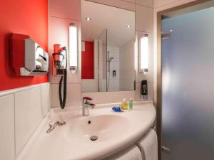 ein Badezimmer mit einem weißen Waschbecken und einem Spiegel in der Unterkunft Ibis Muenchen City Ost in München + 37 Fotos