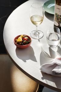 a white table with a bowl of food and a glass of wine at Veriu Green Square in Sydney