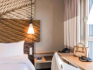 ein Hotelzimmer mit einem Bett und einem Schreibtisch mit einem Telefon in der Unterkunft Ibis Muenchen City Ost in München