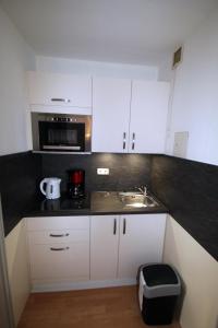 a kitchen with white cabinets and a sink and a microwave at Vier Jahreszeiten 2-6 in Großenbrode