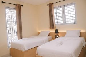 duas camas num quarto com duas janelas em Merlin Hotel em Maumere