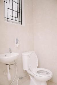 a white bathroom with a toilet and a sink at Merlin Hotel in Maumere