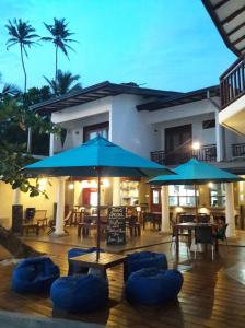 a patio with blue umbrellas and tables and chairs at Beach Inns Holiday Resort in Matara