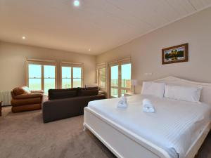 a bedroom with a large white bed and a couch at King Retreat Estate You can honestly walk to Bimbadgen and Hope Estate concerts in Pokolbin