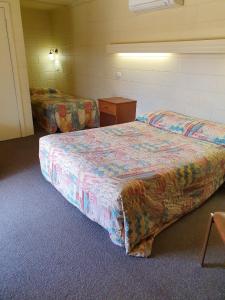 Cette chambre d'hôtel comprend un lit, une table de chevet et un lit sidx sidx. dans l'établissement Opal Inn Hotel, Motel, Caravan Park, à Coober Pedy