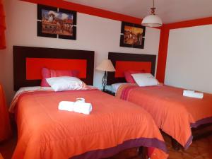 two beds in a room with red and orange at Amaru Hotel Huaraz in Huaraz